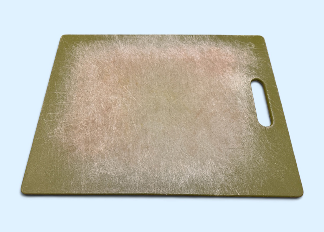Green Plastic Cutting Board with Numerous Grooves from a Knife