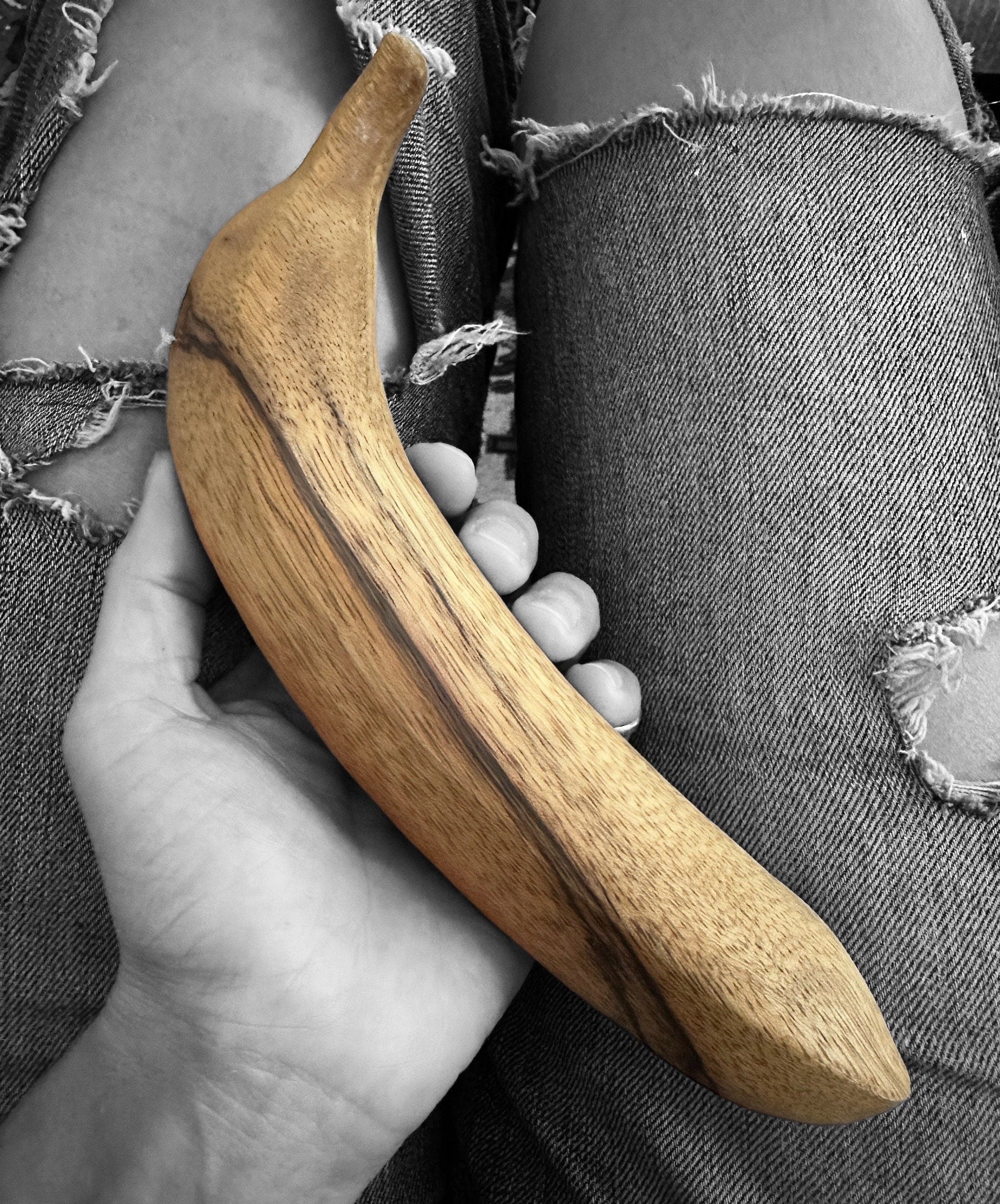 Wooden banana held by a hand on female lap