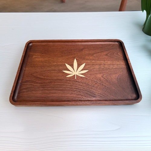 Wooden tray with a cannabis leaf design on a white surface