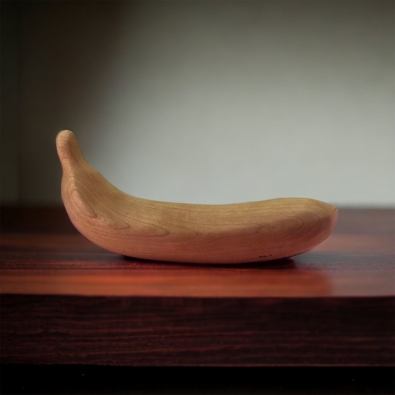 Wooden banana on a wooden surface with a blurred background