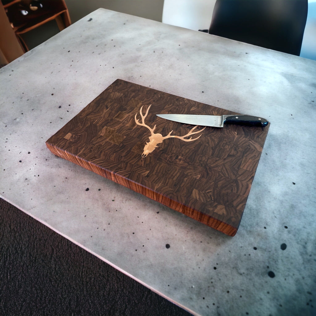 Wooden cutting board with deer design and knife on a speckled countertop