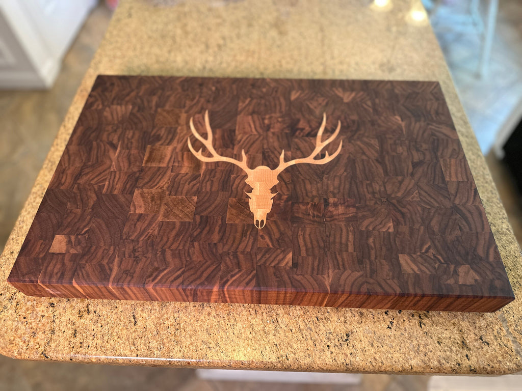 Wooden cutting board with deer skull design on a countertop
