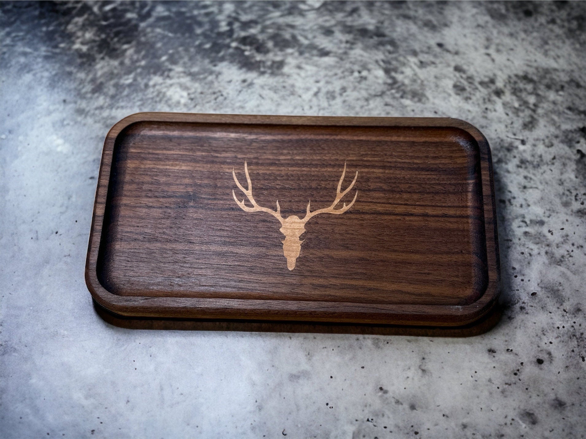 Wooden tray with a deer skull design on a granite surface
