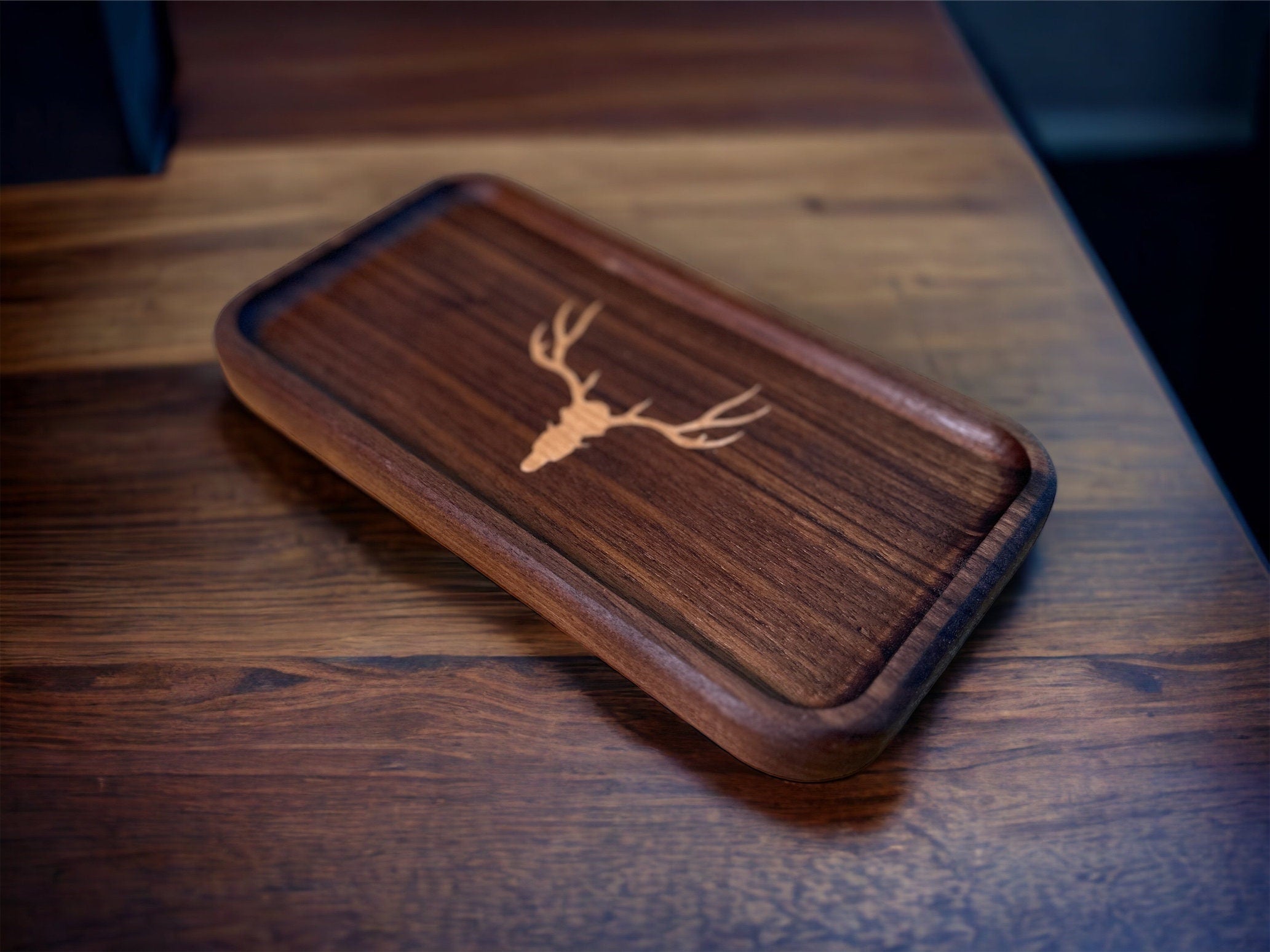 Wooden phone case with deer emblem on a wooden surface