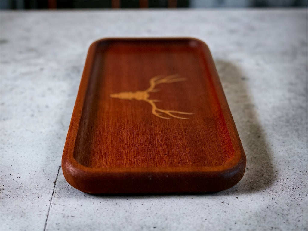 Wooden tray with a deer antler design on a textured surface