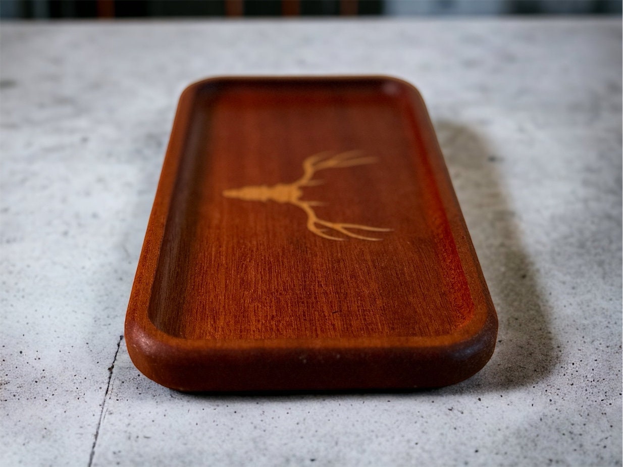 Wooden tray with a deer antler design on a textured surface