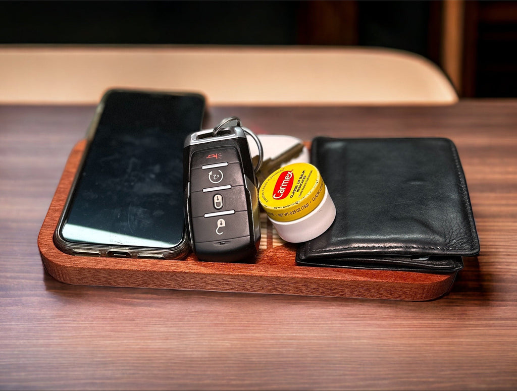 Phone, keys, wallet, and chapstick on a wooden tray on a wooden table