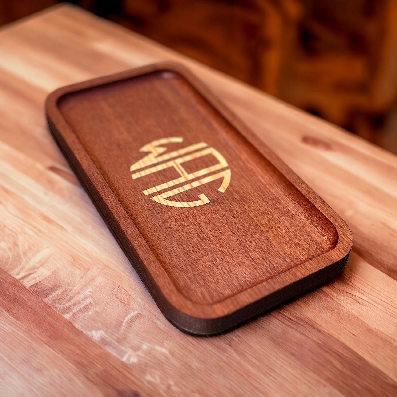 Wooden valet tray with a monogram on a wooden surface