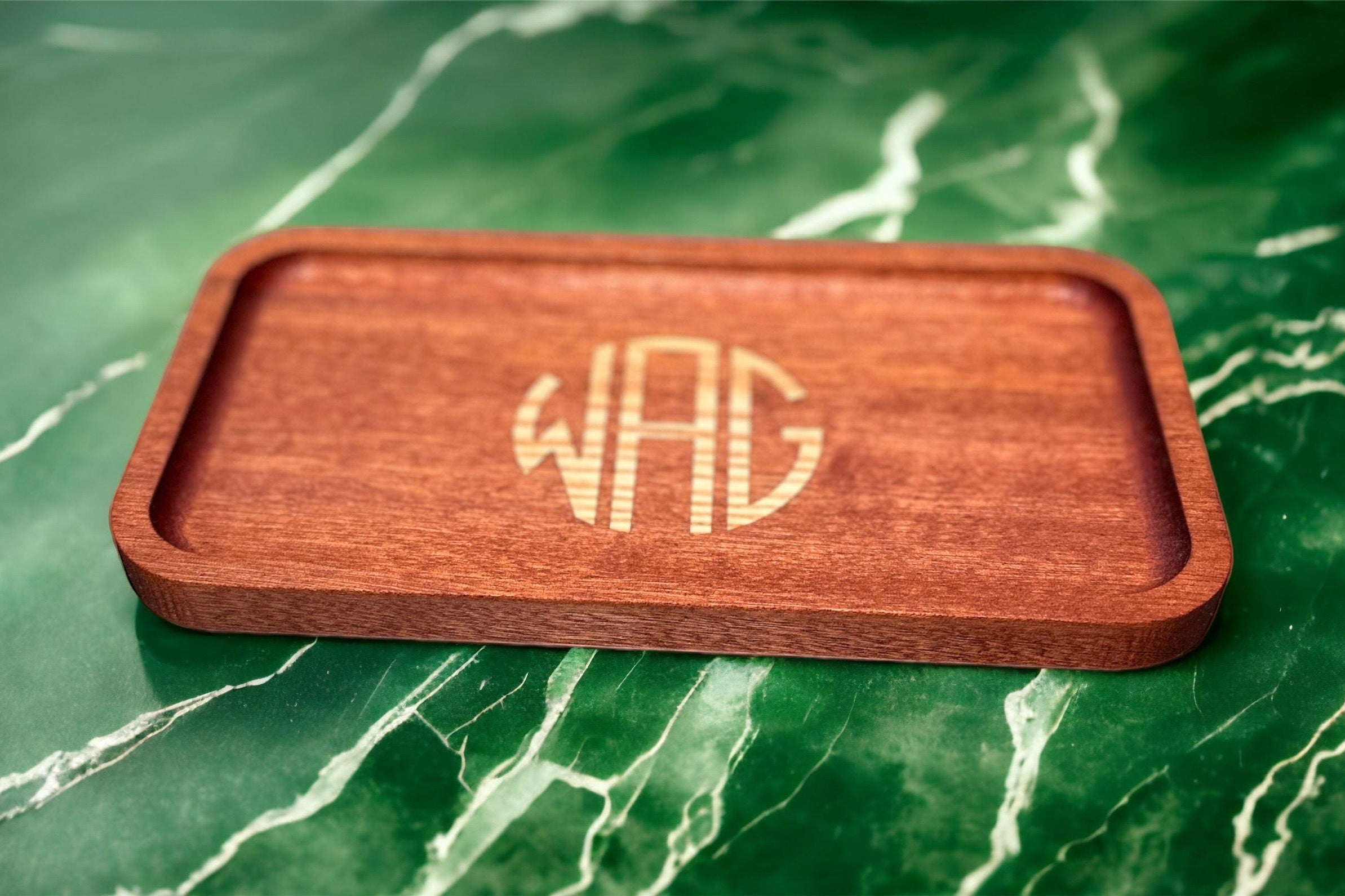Wooden tray with engraved monogram on a green marble surface