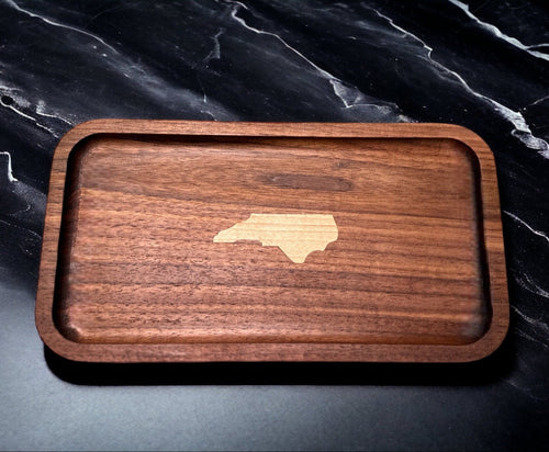 Wooden tray with an inlayed piece of wood depicting the state of North Carolina on a dark marble surface