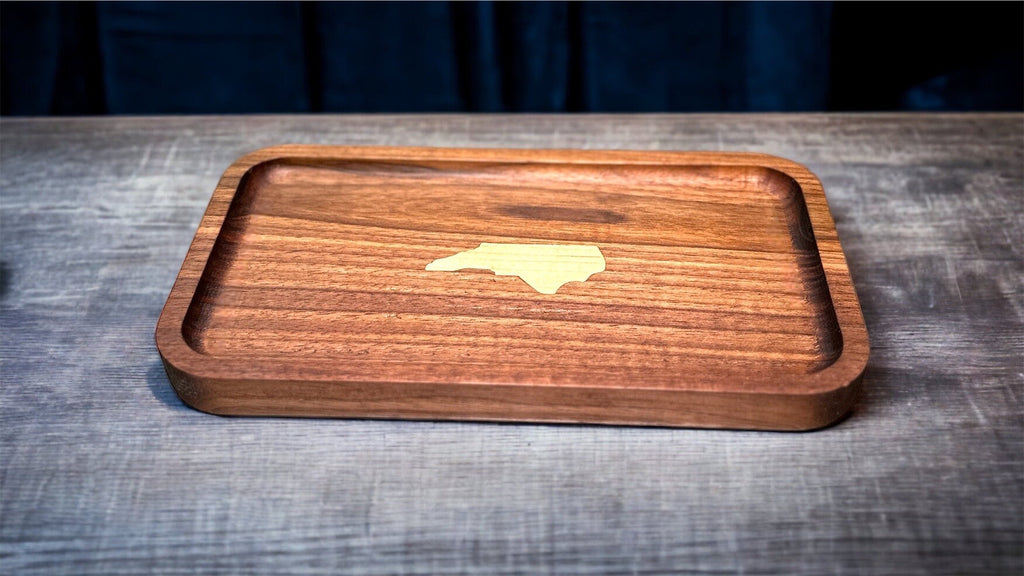 Wooden tray with a cutout of the state of North Carolina on a wooden surface.