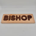 Wooden name puzzle with 'BISHOP' engraved on a plain background