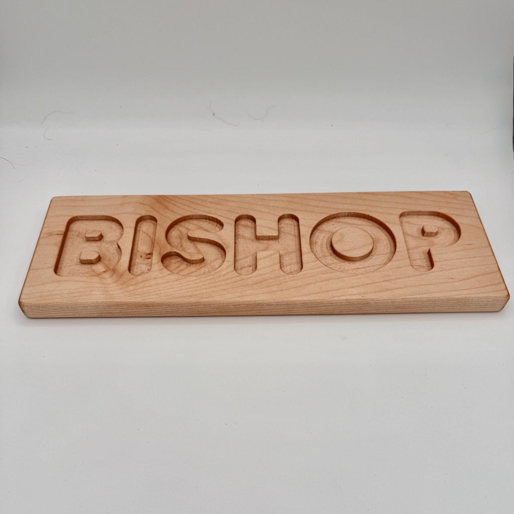 Wooden nameplate with 'BISHOP' engraved on a white background
