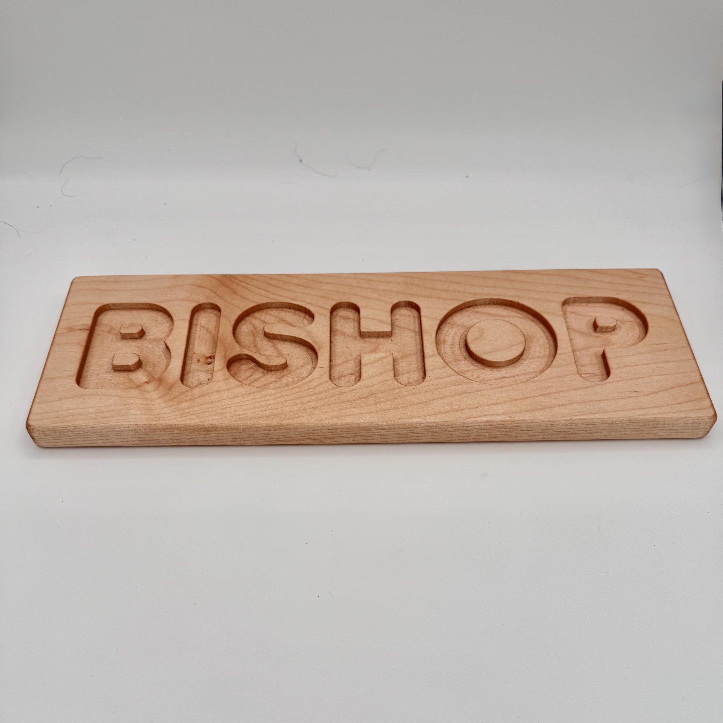 Wooden nameplate with 'BISHOP' engraved on a white background