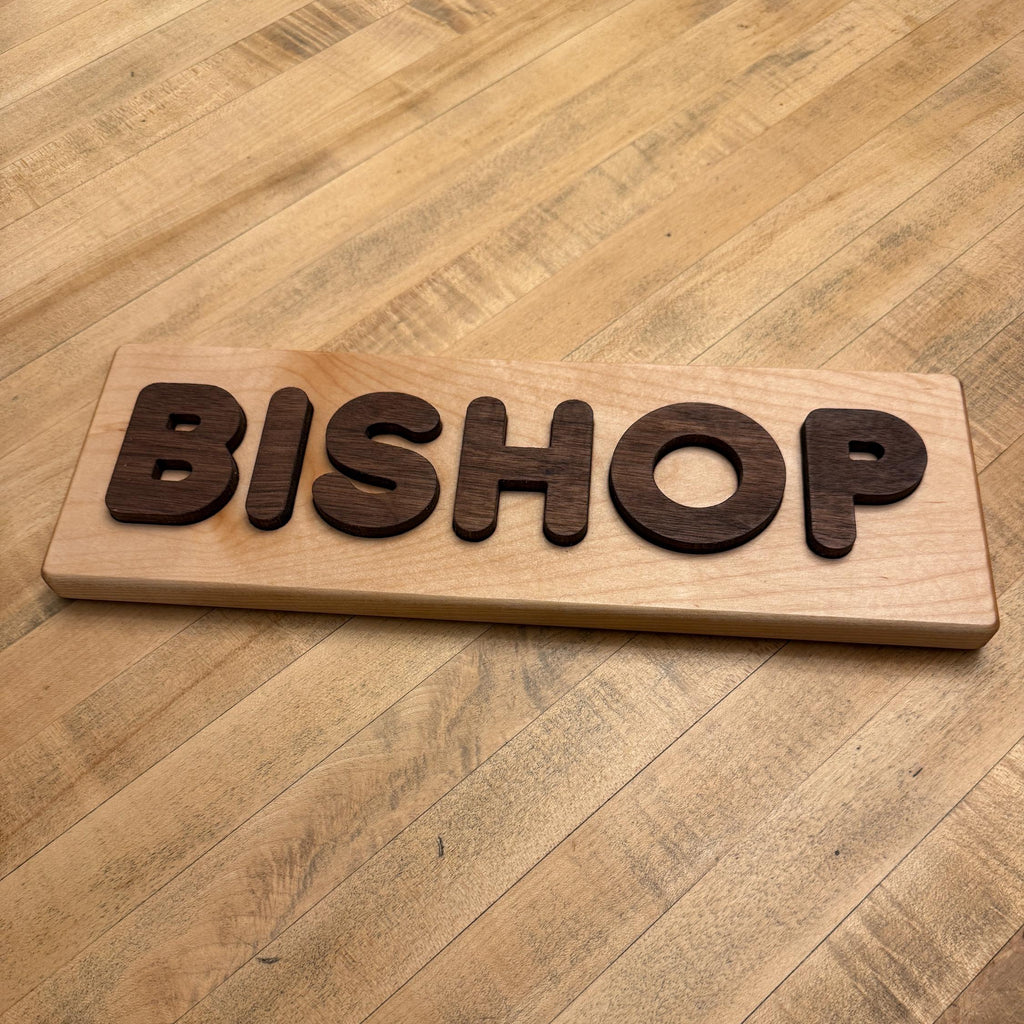 Wooden sign with the word 'BISHOP' on a wooden table.