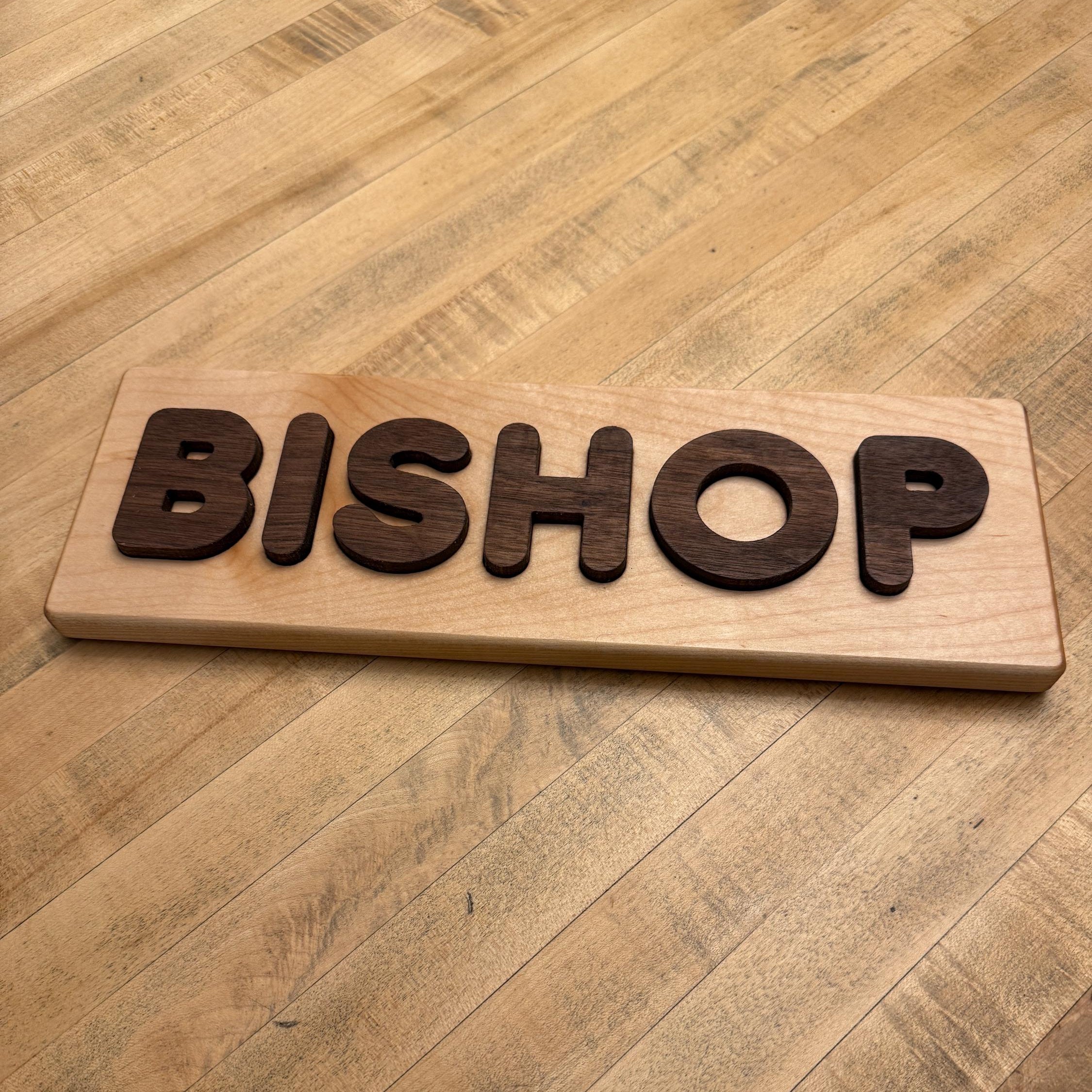Wooden sign with the word 'BISHOP' on a wooden table.