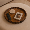Wooden tray with a book and remote control on a beige ottoman