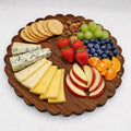 Wooden board with assorted cheeses, fruits, and crackers on a white background