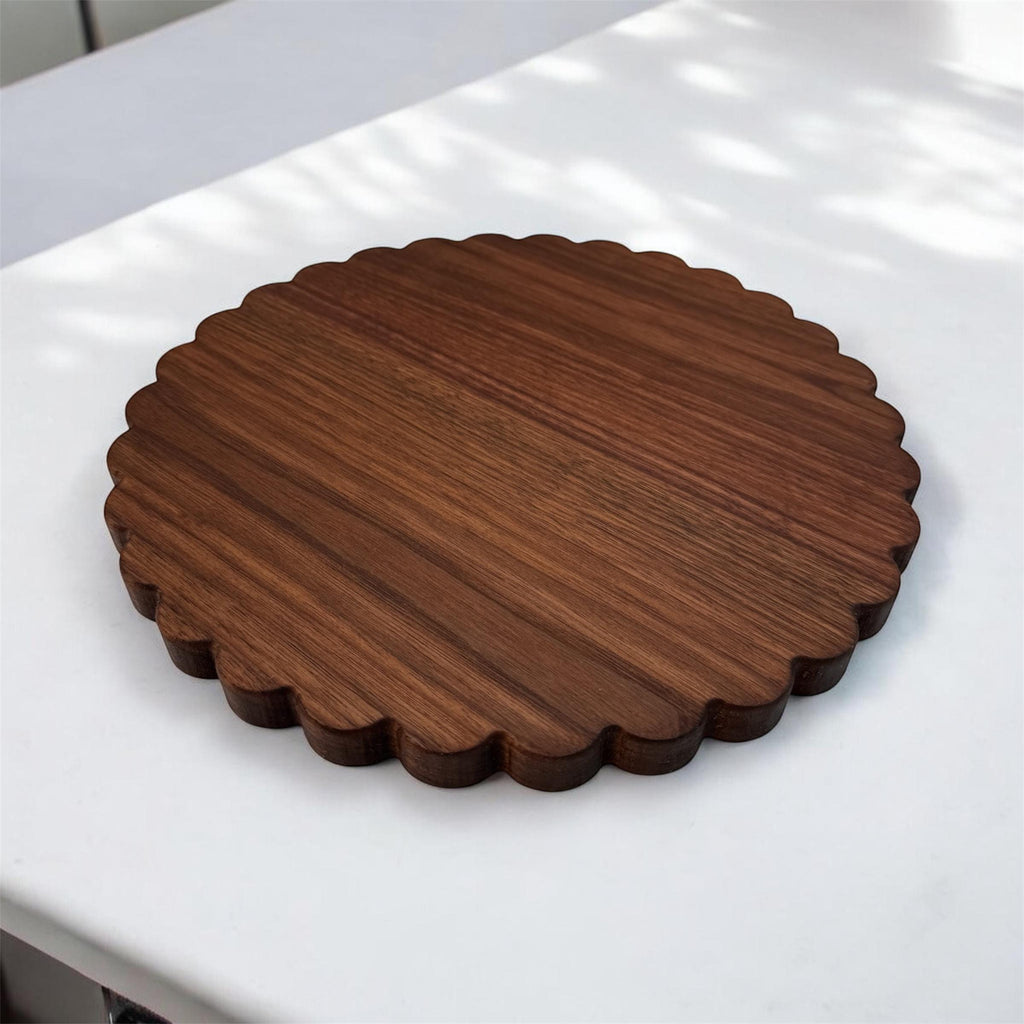 Round wooden scalloped cutting board on marble surface