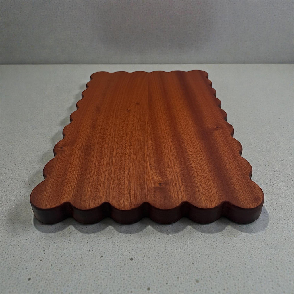Wooden cutting board with scalloped edge on a gray background