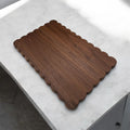 Wooden cutting board with scalloped edge on a marble surface