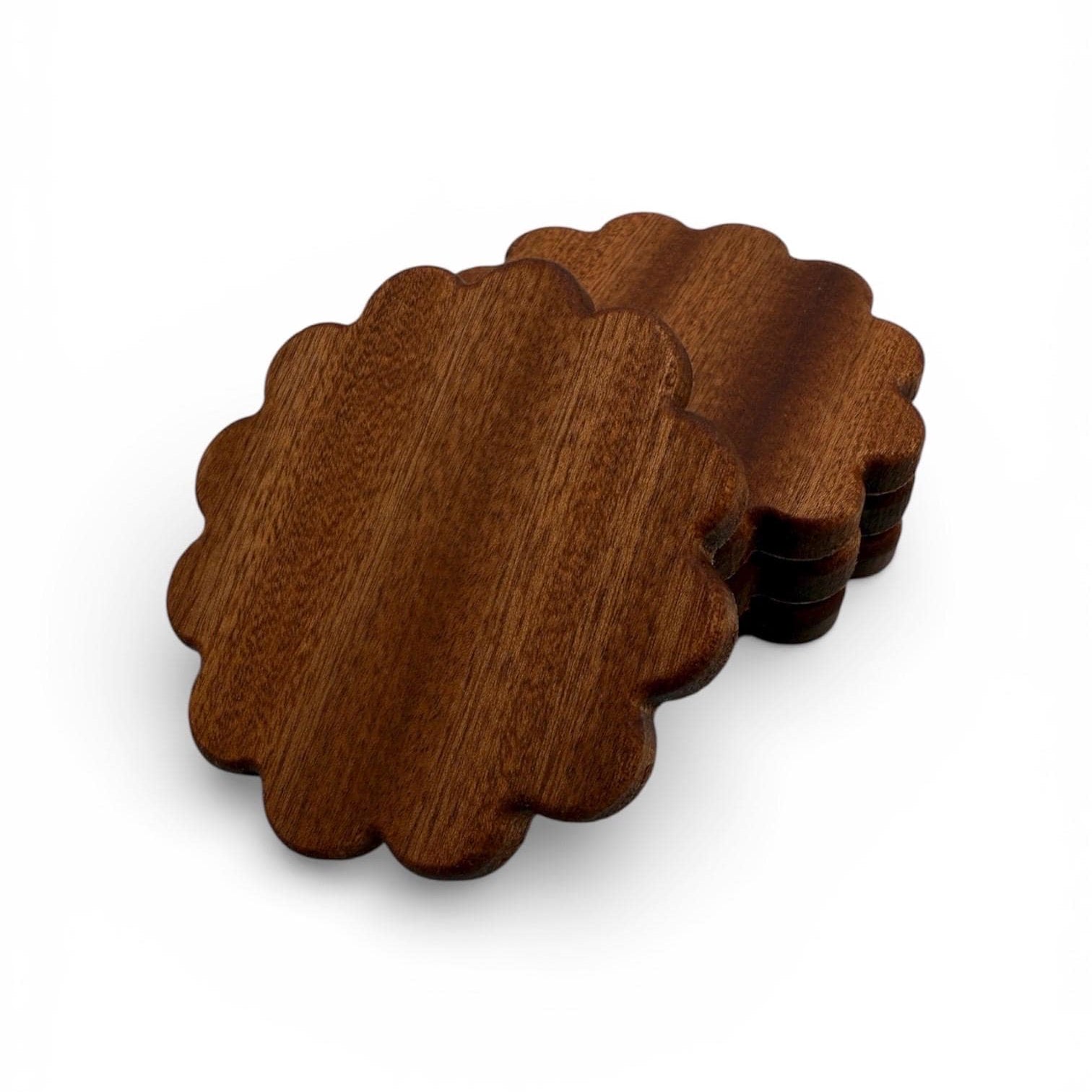 Set of four wooden coasters with scalloped edges on a white background
