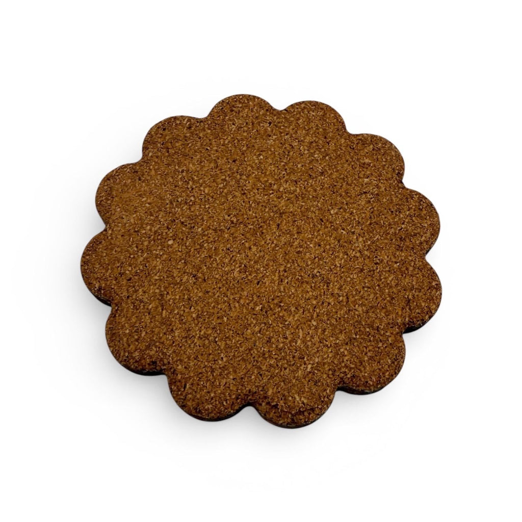 The cork bottom of a coaster with scalloped edge on a white background