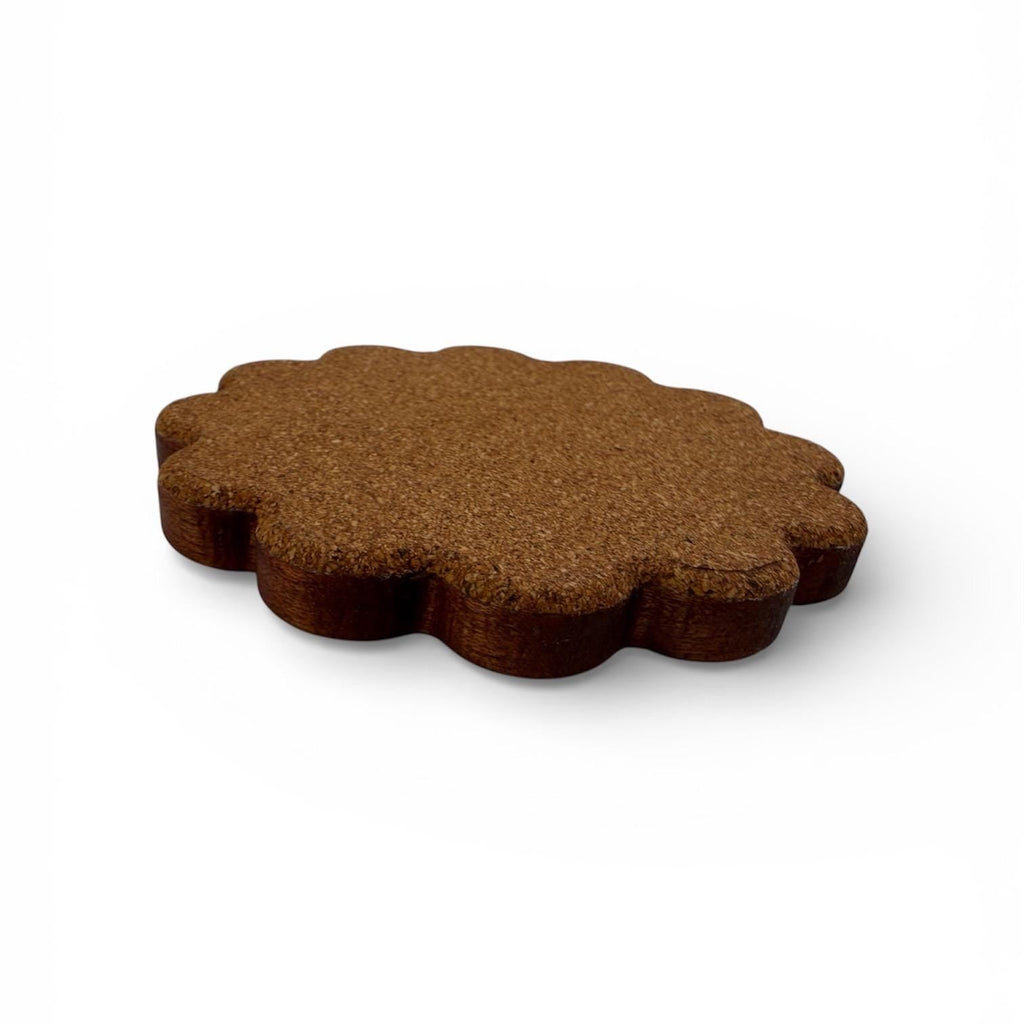 The cork bottom of a coaster with scalloped edge on a white background