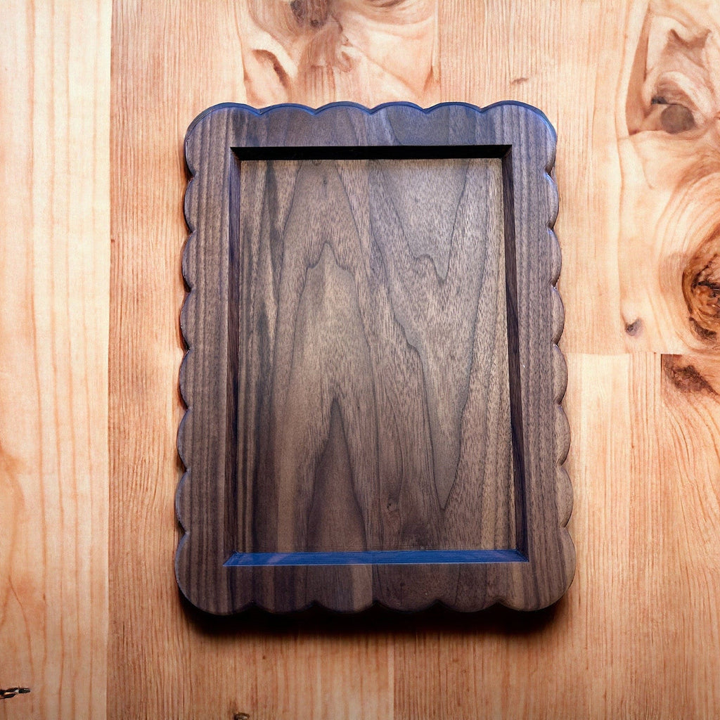 Wooden picture frame with scalloped edge on a wooden surface