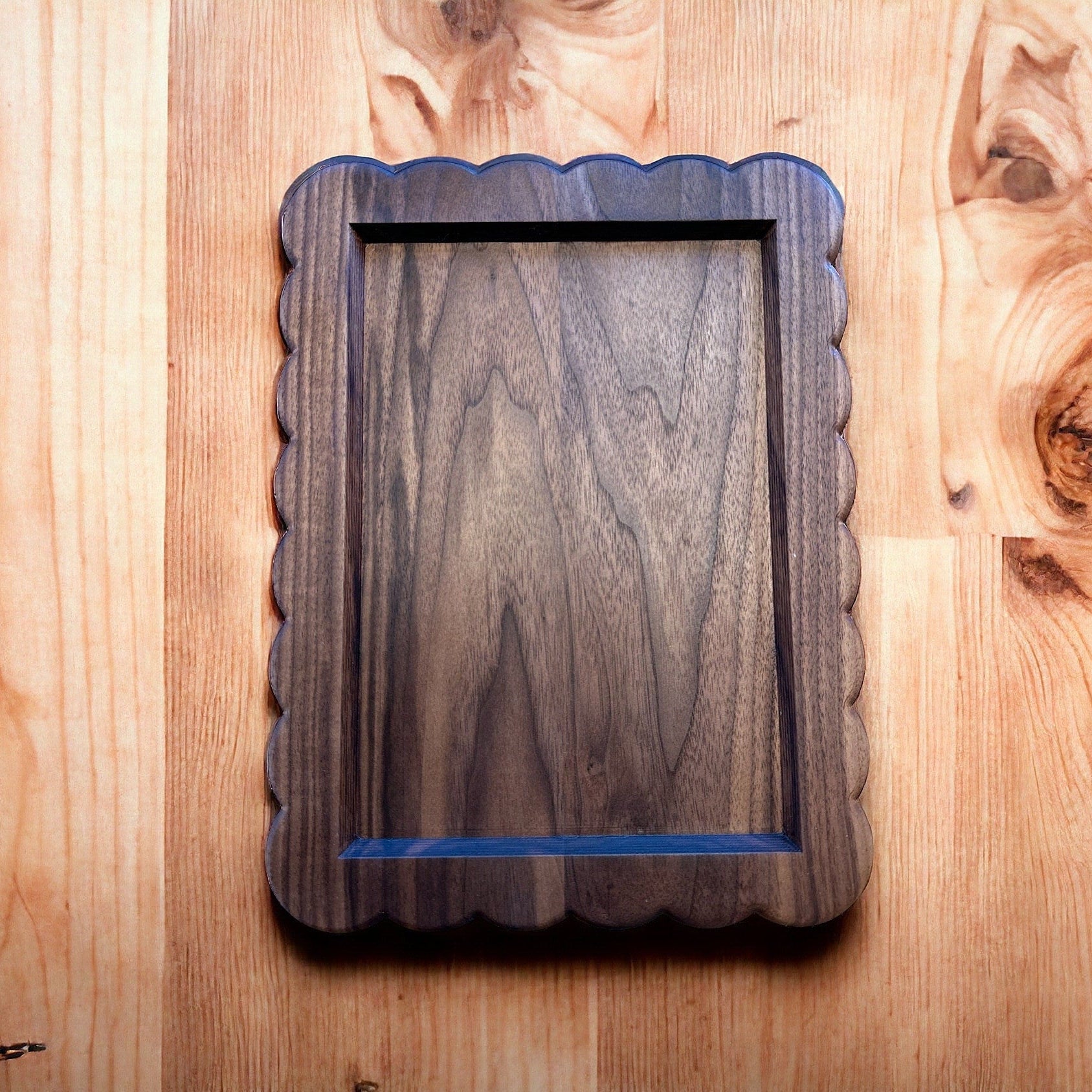 Wooden picture frame with scalloped edge on a wooden surface
