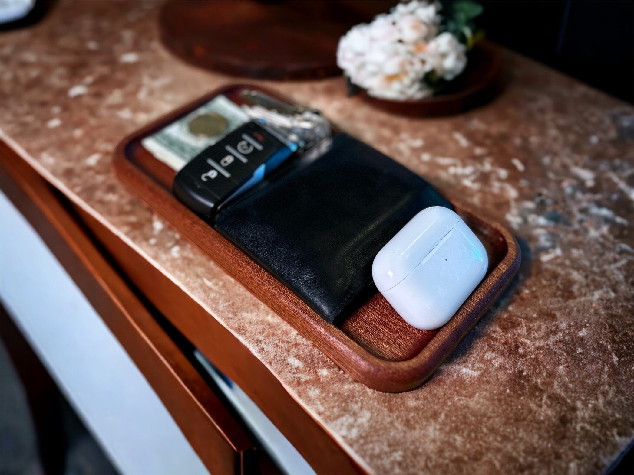 Wooden dock with wireless earbuds and charging case on a textured surface