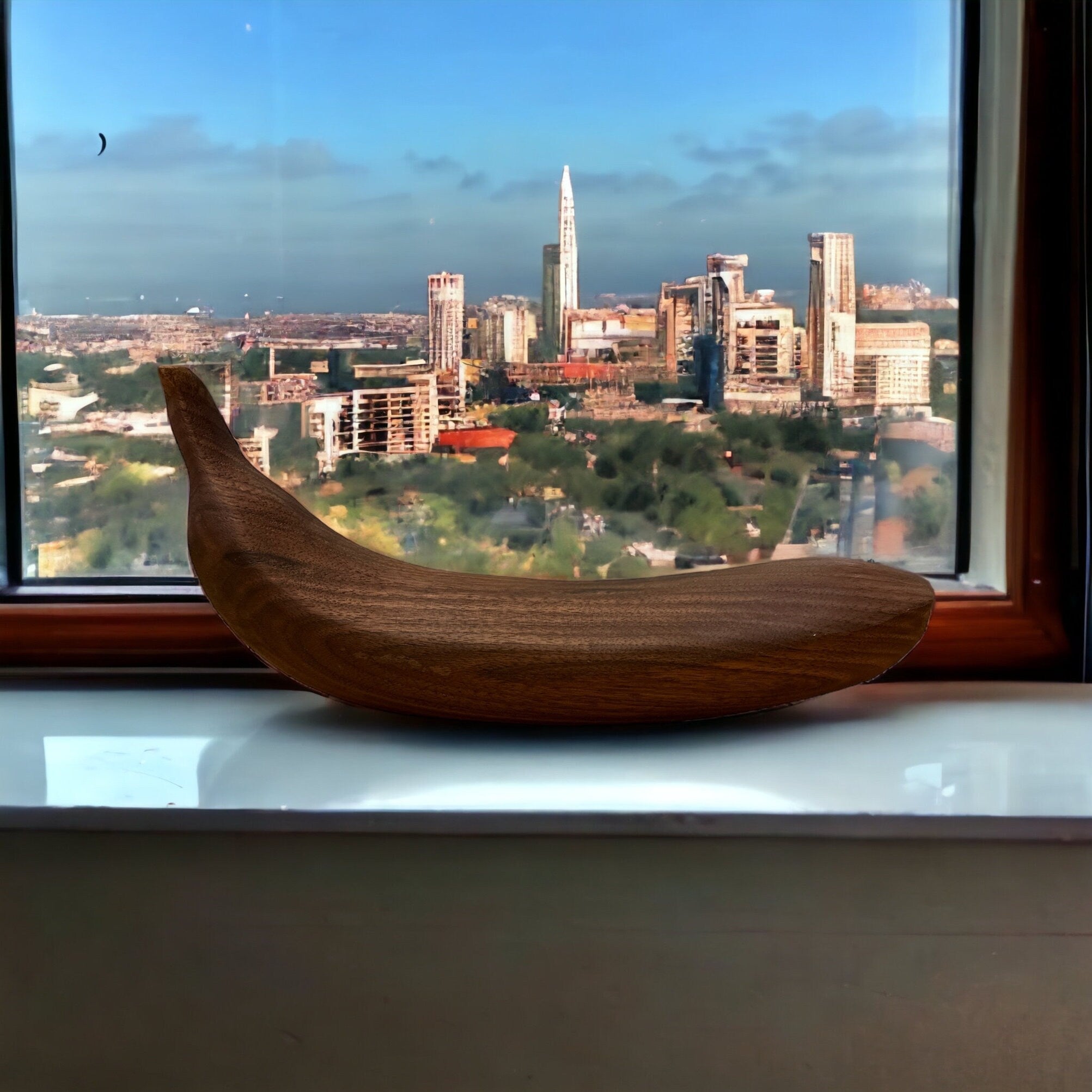 Wooden banana on a windowsill with a cityscape view outside