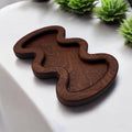 Wooden tray with a wavy design on a white surface with green plants in the background